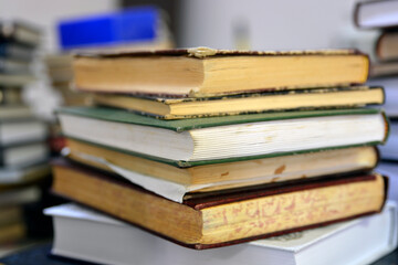 A pile of old books stacked on top of each other in a close-up shot
