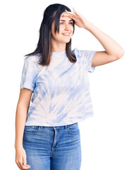 Young beautiful girl wearing casual t shirt very happy and smiling looking far away with hand over head. searching concept.