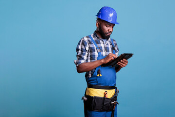 Portrait of a builder working with a digital tablet, shopping online for materials needed for the...