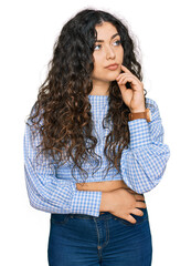 Young hispanic girl wearing casual clothes with hand on chin thinking about question, pensive...