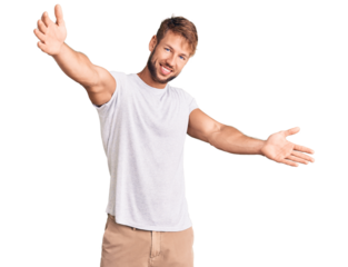 Young caucasian man wearing casual white tshirt looking at the camera smiling with open arms for hug. cheerful expression embracing happiness.