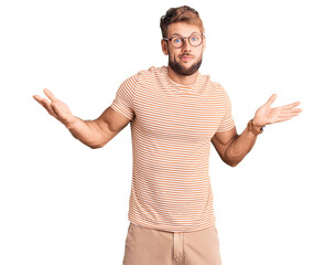 Young caucasian man wearing casual clothes and glasses clueless and confused expression with arms...