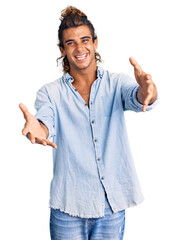 Young hispanic man wearing summer style smiling cheerful offering hands giving assistance and acceptance.