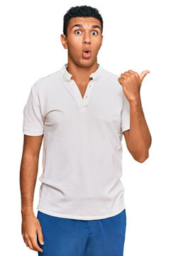 Young arab man wearing casual clothes surprised pointing with hand finger to the side, open mouth amazed expression.