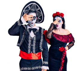 Young couple wearing mexican day of the dead costume over background peeking in shock covering face and eyes with hand, looking through fingers with embarrassed expression.