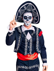 Young man wearing day of the dead costume over background pointing finger up with successful idea. exited and happy. number one.