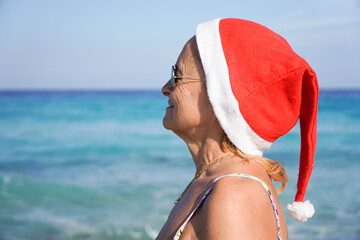 Woman with santa hat looking at the sea. Christmas holiday in summertime