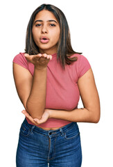 Young hispanic girl wearing casual t shirt looking at the camera blowing a kiss with hand on air being lovely and sexy. love expression.