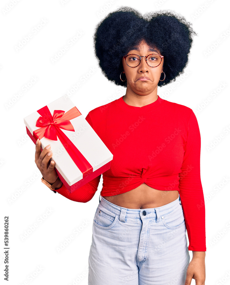 Wall mural Young african american girl holding gift depressed and worry for distress, crying angry and afraid. sad expression.