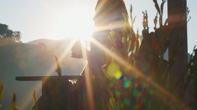 Woman drinks mate tea and enjoys sunrise in Brazilian mountains from the wooden terrace