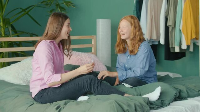 Girlfriends, Students Sit at Home on Bed and Paint Nails. Two Sisters Having Fun, Chatting, Body Positive. Adolescence Concept. Mental Health.