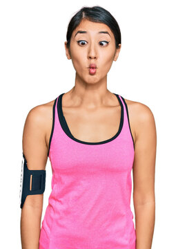 Beautiful asian young sport woman wearing sportswear and arm band making fish face with lips, crazy and comical gesture. funny expression.