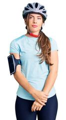 Beautiful caucasian young woman wearing bike helmet with serious expression on face. simple and natural looking at the camera.