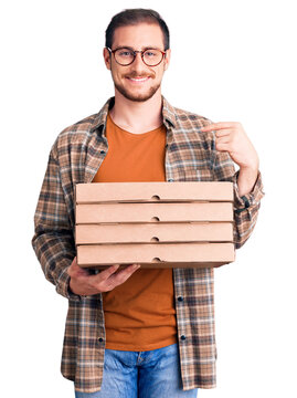 Young handsome caucasian man holding delivery pizza box pointing finger to one self smiling happy and proud