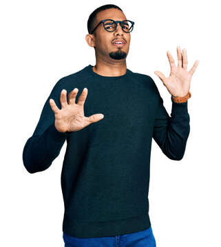 Young african american man wearing casual clothes and glasses afraid and terrified with fear expression stop gesture with hands, shouting in shock. panic concept.