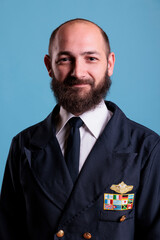 Smiling airplane pilot wearing uniform medium close up portrait, plane captain looking at camera. Middle age aviator with civil badge on professional suit, aircrew member