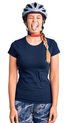 Beautiful caucasian woman wearing bike helmet sticking tongue out happy with funny expression. emotion concept.