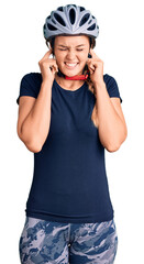 Beautiful caucasian woman wearing bike helmet covering ears with fingers with annoyed expression for the noise of loud music. deaf concept.