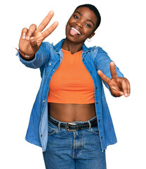 Young african american woman wearing casual clothes smiling with tongue out showing fingers of both...