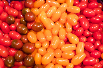 Texture of tomatoes in basket at the market place. Long plum tomato texture background. Fresh small red and yellow cherry tomatoes pattern, mini organic cocktail tomate mix selective focus