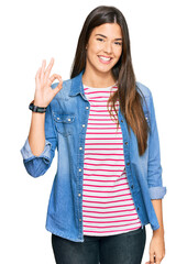 Young brunette woman wearing casual clothes smiling positive doing ok sign with hand and fingers. successful expression.