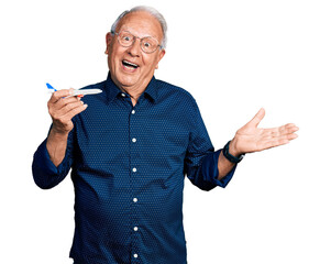 Senior man with grey hair holding airplane toy celebrating achievement with happy smile and winner expression with raised hand