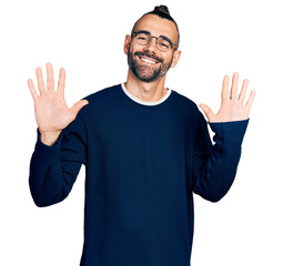 Hispanic man with ponytail wearing casual sweater and glasses showing and pointing up with fingers number ten while smiling confident and happy.