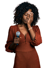 African woman with curly hair singing song using microphone yawning tired covering half face, eye and mouth with hand. face hurts in pain.