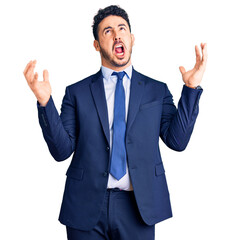 Young hispanic man wearing business clothes crazy and mad shouting and yelling with aggressive expression and arms raised. frustration concept.