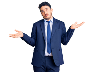 Young hispanic man wearing business clothes clueless and confused expression with arms and hands raised. doubt concept.