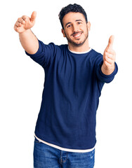 Fototapeta premium Young hispanic man wearing casual clothes looking at the camera smiling with open arms for hug. cheerful expression embracing happiness.