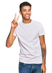 Naklejka premium Young handsome african american man wearing casual white tshirt showing and pointing up with fingers number two while smiling confident and happy.