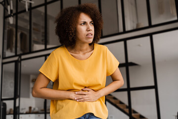 Ulcer or gastritis stomach ache. Sick african american girl hold abdomen because it hurts....