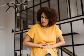 Stomach pain. Sick african american girl hold abdomen because it hurts. Pancreatitis disease of...