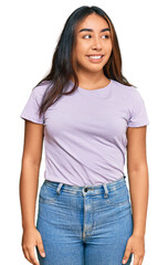 Obraz premium Young latin woman wearing casual clothes looking away to side with smile on face, natural expression. laughing confident.