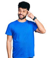 Young arab man with beard wearing casual blue t shirt smiling pointing to head with one finger,...