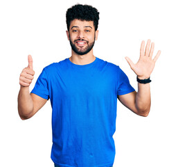 Young arab man with beard wearing casual blue t shirt showing and pointing up with fingers number six while smiling confident and happy.