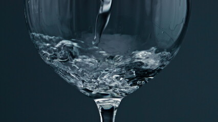 Closeup pure water filling wine glass. Air bubbles rising up from cup bottom