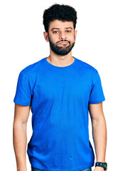 Young arab man with beard wearing casual blue t shirt looking sleepy and tired, exhausted for fatigue and hangover, lazy eyes in the morning.