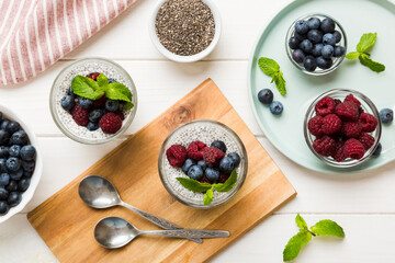 Healthy breakfast or morning with chia seeds vanilla pudding raspberry and blueberry berries on table background, vegetarian food, diet and health concept. Chia pudding with raspberry and blueberry