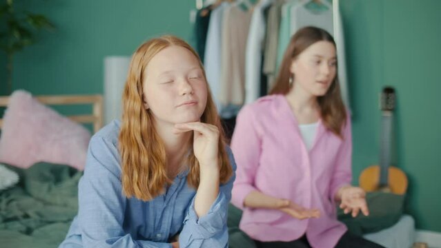 Two Girlfriends Arguing Sitting Apart at Home, Sisters Having Conflict, Girl in the Foreground Ignoring Angry Friend Shouting and Gesturing in Background, Teenage Friendship Problems. Mental Health
