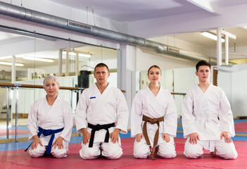 Group of athletes in kimono sit on a tatami before preparing for sparring