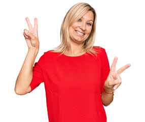 Middle age caucasian woman wearing casual clothes smiling looking to the camera showing fingers doing victory sign. number two.