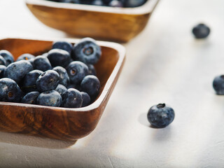 On a white background, two bowls with fresh blueberries. Close-up. Lots of vitamins, antioxidants, light summer dessert, confectionery ingredient. Cooking, medicine, ecology.