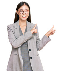 Young chinese woman wearing business clothes smiling and looking at the camera pointing with two...