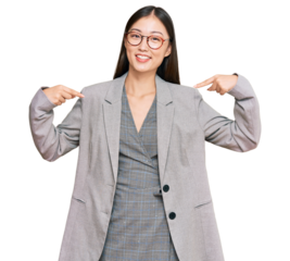 Young chinese woman wearing business clothes looking confident with smile on face, pointing oneself with fingers proud and happy.