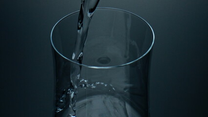 Pure liquid pouring glass top view closeup. Refreshing mineral water splashing