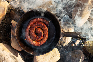 Sausage on the pan over an open fire. Preparing food in nature.