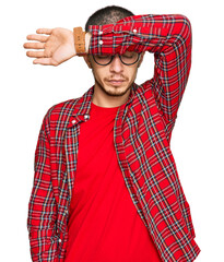 Hispanic young man wearing casual clothes covering eyes with arm, looking serious and sad....