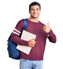 Hispanic handsome young man wearing student backpack and notebook smiling happy and positive, thumb...